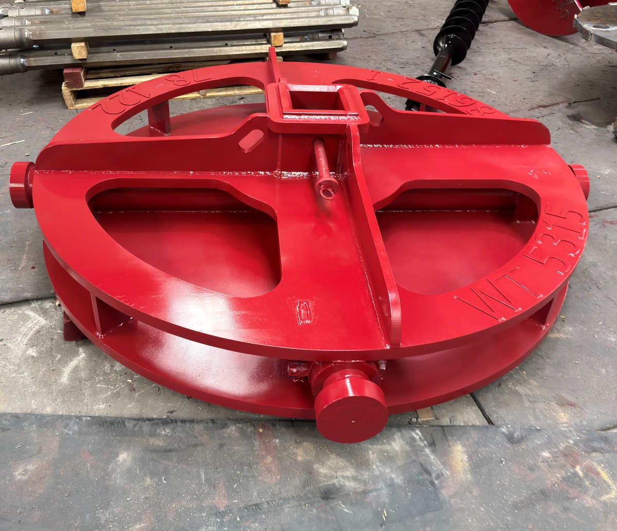  A red metal drilling attachment with silver raised teeth positioned beside a white sign with the initials 'JM' on it.
